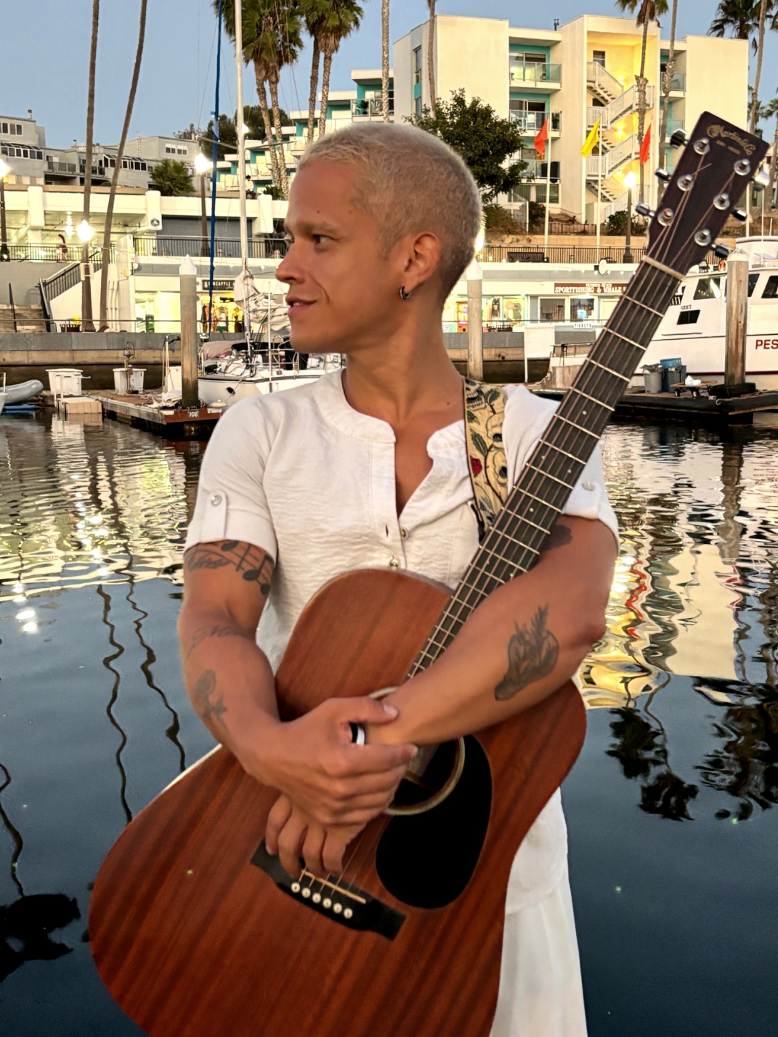 Pedro holding an acoustic guitar at the marina