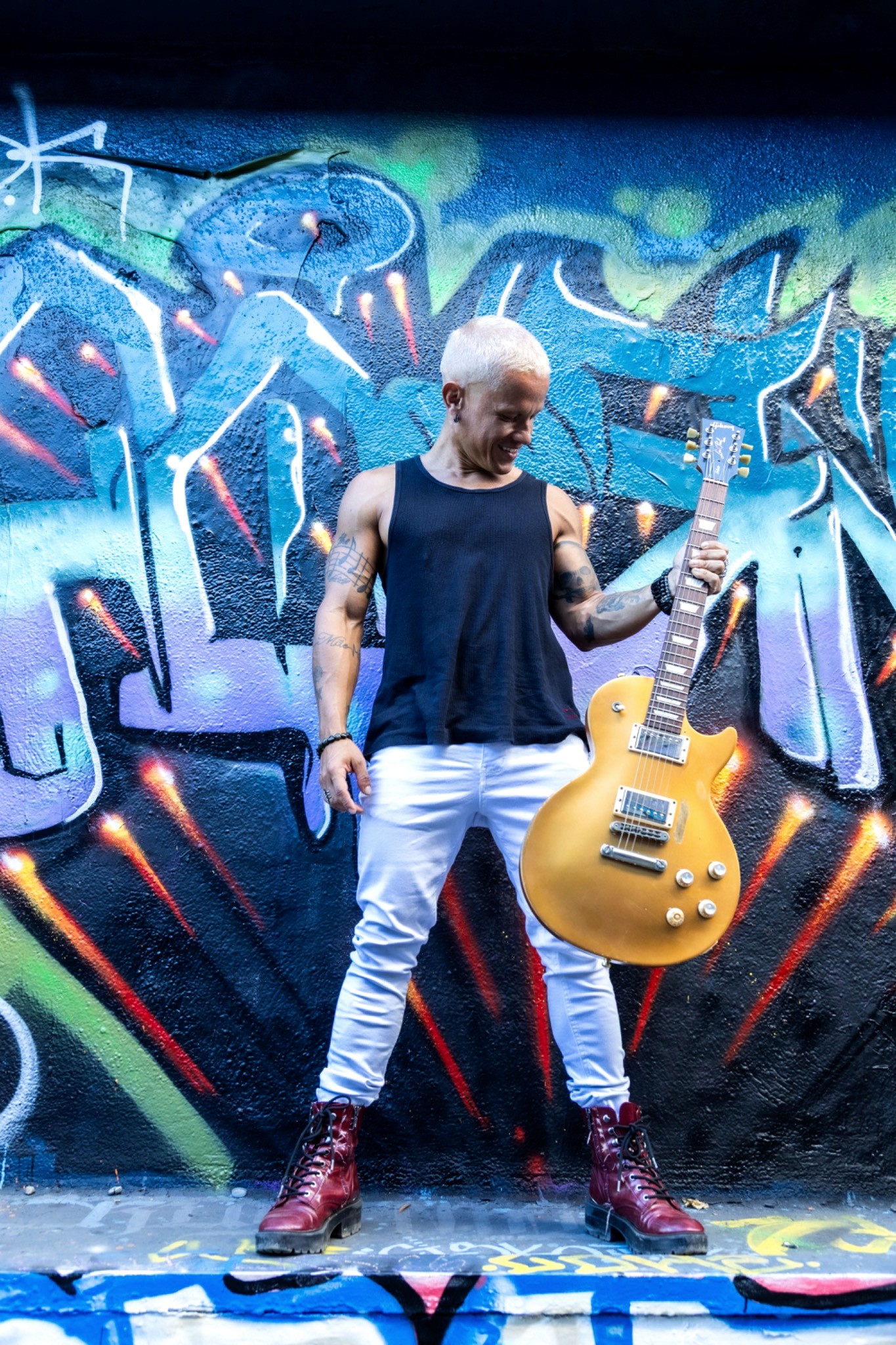 Pedro with electric guitar in front of vibrant street art